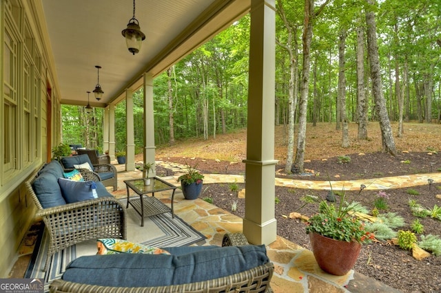 view of patio featuring an outdoor living space, a porch, and a forest view