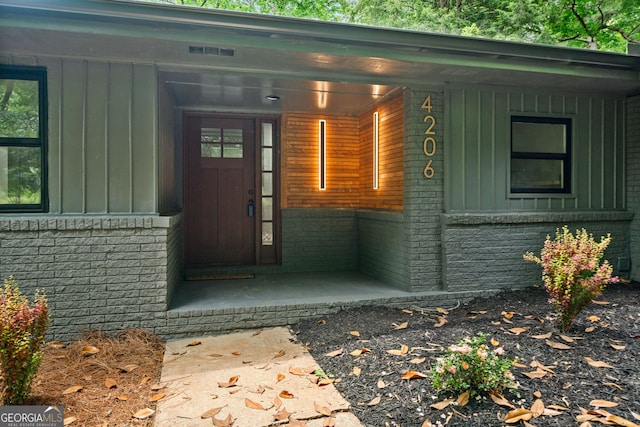 entrance to property with board and batten siding and brick siding