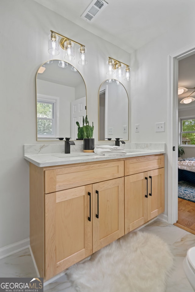 ensuite bathroom featuring double vanity and baseboards