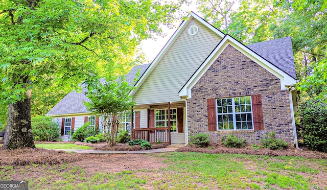 view of front of property with covered porch, brick siding, and a shingled roof