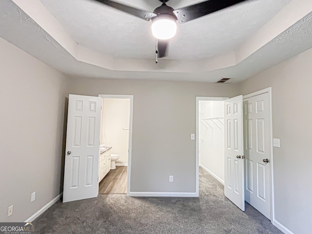 unfurnished bedroom featuring ensuite bath, visible vents, baseboards, a closet, and dark carpet