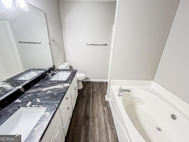 bathroom featuring a sink, double vanity, toilet, wood finished floors, and a bath