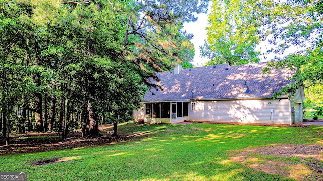 back of house with a sunroom, a lawn, and roof with shingles