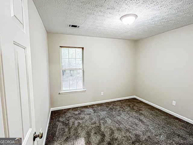 empty room with a textured ceiling, visible vents, baseboards, and carpet