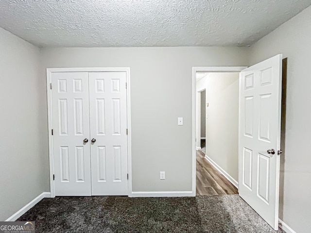 unfurnished bedroom with carpet floors, baseboards, a closet, and a textured ceiling