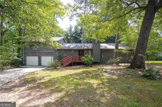 view of front of property with concrete driveway, a front lawn, a deck, stairs, and an attached garage