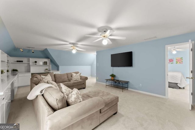 living room with baseboards, ceiling fan, light carpet, and vaulted ceiling