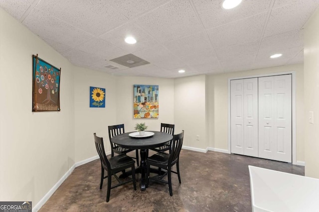 dining space featuring recessed lighting, baseboards, concrete floors, and a paneled ceiling