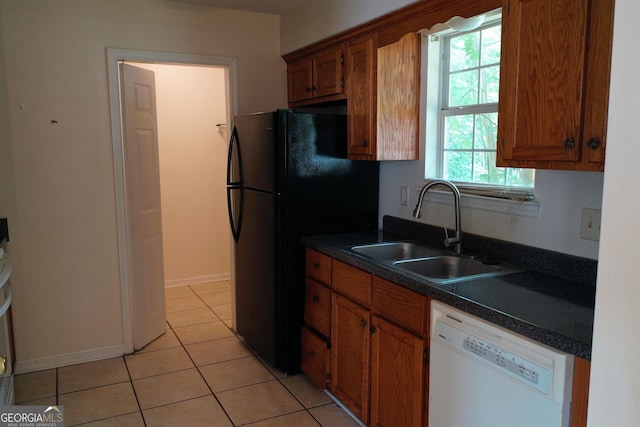 302 Kensington Cir, Warner Robins, GA 31093 - kitchen with brown cabinetry, freestanding refrigerator, dark countertops, a sink, and dishwasher