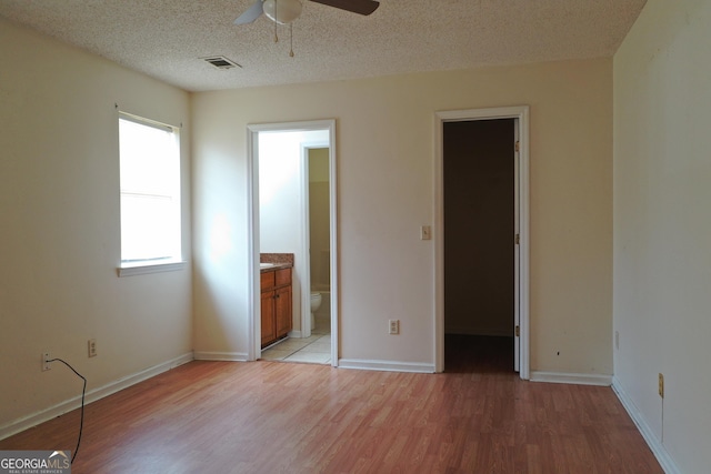 302 Kensington Cir, Warner Robins, GA 31093 - unfurnished bedroom featuring connected bathroom, a walk in closet, light wood-style floors, a textured ceiling, and visible vents