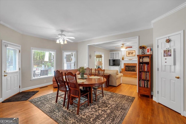 6034 Addington Dr NW, Acworth, GA 30101 - dining area with a ceiling fan, a fireplace, baseboards, ornamental molding, and light wood-style flooring