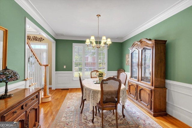 6034 Addington Dr NW, Acworth, GA 30101 - dining room featuring crown molding, an inviting chandelier, light wood-style flooring, and a wainscoted wall