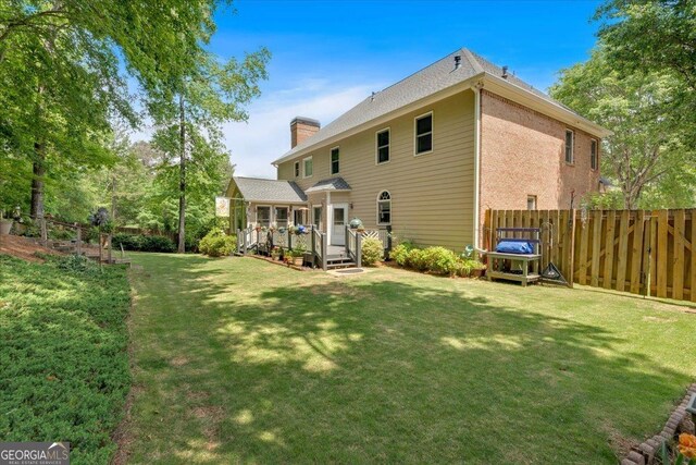 6034 Addington Dr NW, Acworth, GA 30101 - rear view of house featuring fence, a wooden deck, a chimney, and a lawn