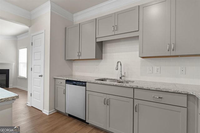 kitchen featuring backsplash, wood finished floors, dishwasher, a sink, and gray cabinetry