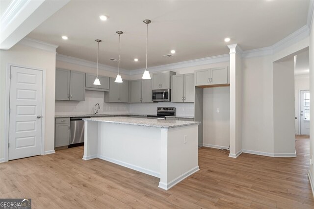 kitchen with a kitchen island, gray cabinetry, baseboards, ornamental molding, and stainless steel appliances