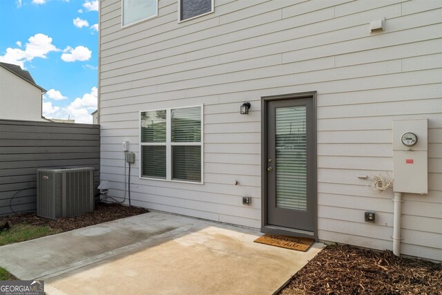 entrance to property with central air condition unit, fence, and a patio area