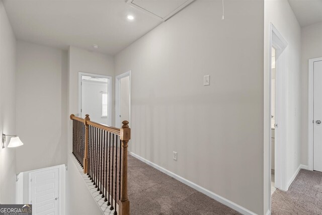 hallway featuring carpet floors, attic access, recessed lighting, baseboards, and an upstairs landing