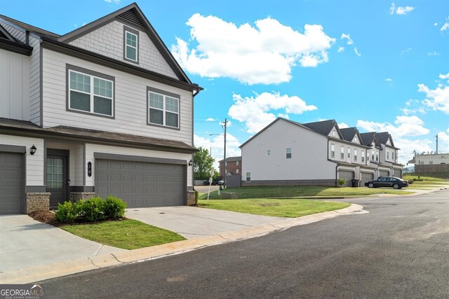 exterior space with concrete driveway, an attached garage, a residential view, and a yard