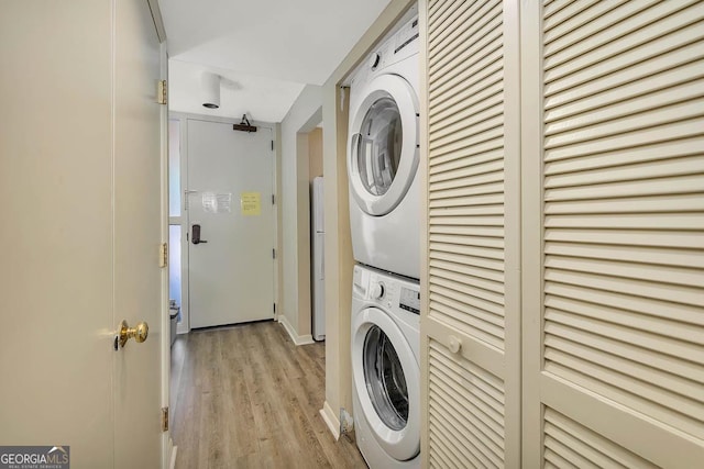 clothes washing area featuring laundry area, stacked washer / dryer, and light wood-type flooring