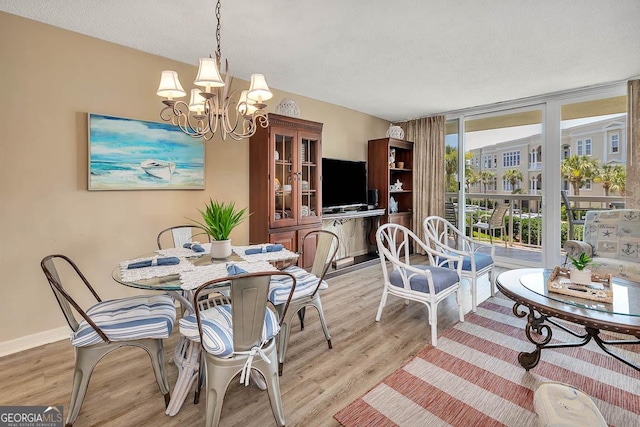 dining area featuring a wall of windows, a textured ceiling, light wood-type flooring, baseboards, and a notable chandelier