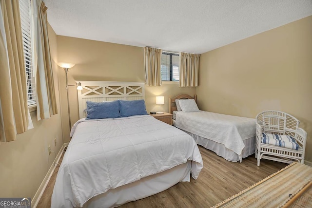 bedroom featuring baseboards, a textured ceiling, and wood finished floors