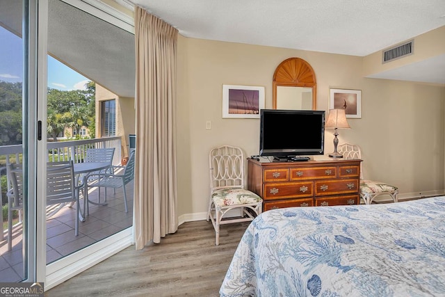bedroom with access to outside, a textured ceiling, baseboards, wood finished floors, and visible vents