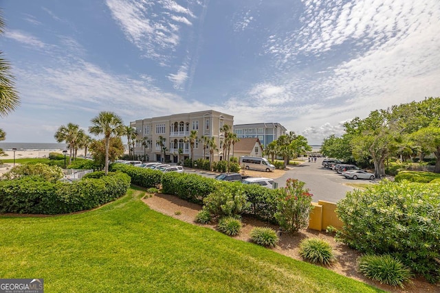 view of property's community featuring a lawn and uncovered parking