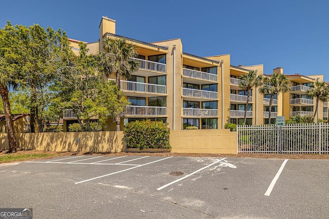 view of property featuring fence and uncovered parking