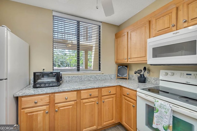 kitchen with a toaster, light stone counters, ceiling fan, and white appliances