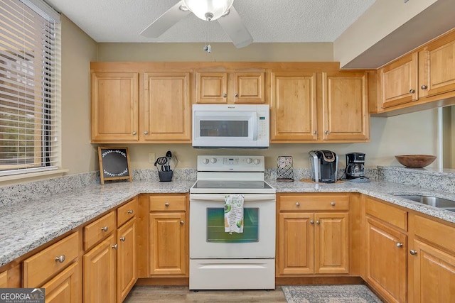 kitchen with light stone countertops, ceiling fan, light wood finished floors, white appliances, and a textured ceiling