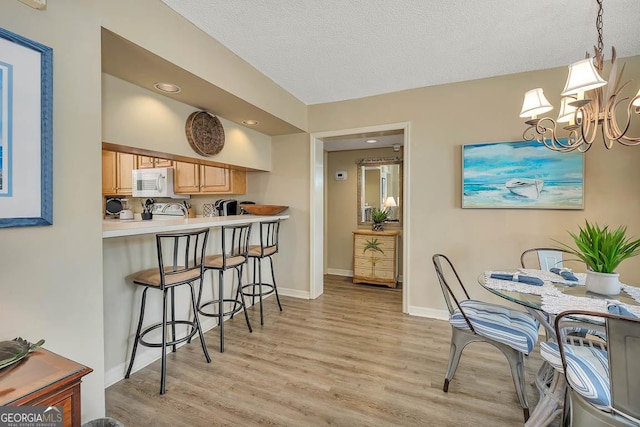 dining space featuring an inviting chandelier, baseboards, recessed lighting, a textured ceiling, and light wood finished floors