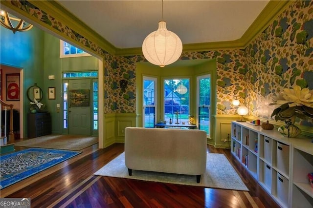 sitting room with wallpapered walls, wainscoting, healthy amount of natural light, wood finished floors, and ornamental molding