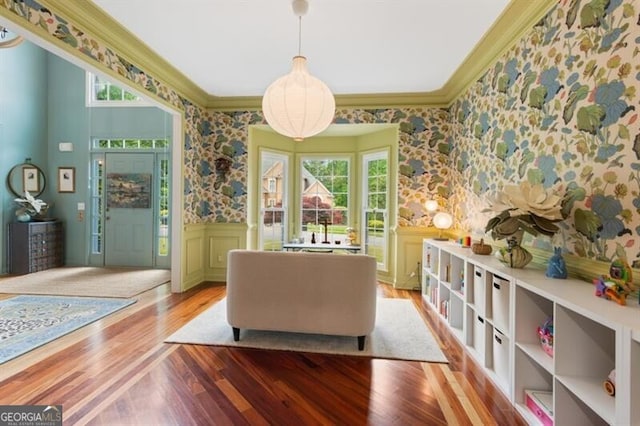 sitting room with wallpapered walls, wood finished floors, a wainscoted wall, and crown molding