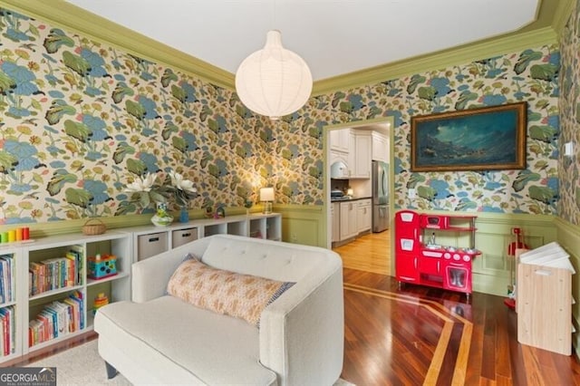 sitting room with wallpapered walls, a wainscoted wall, crown molding, and light wood-type flooring