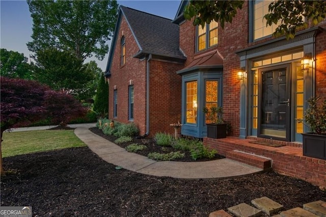 view of side of property featuring brick siding and a shingled roof