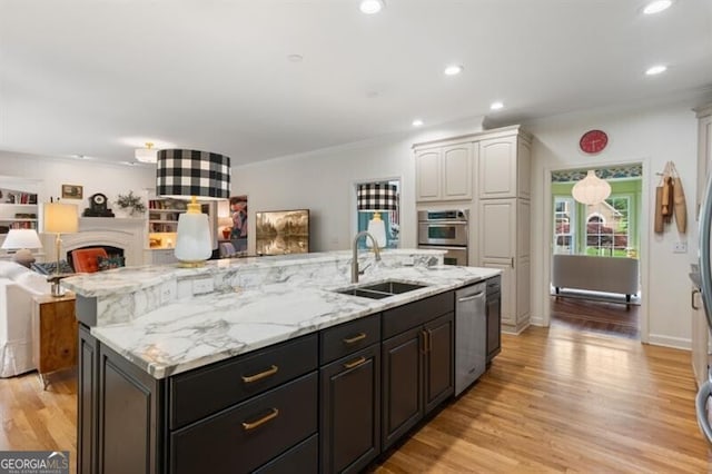 kitchen featuring a sink, stainless steel appliances, open floor plan, a kitchen island with sink, and white cabinets