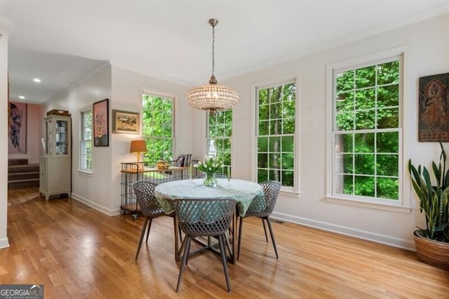 dining area featuring crown molding, baseboards, light wood-style flooring, and stairs