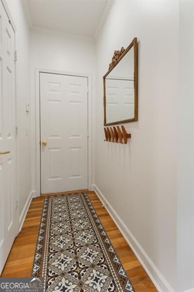 entryway with crown molding, light wood-type flooring, and baseboards
