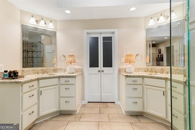 bathroom with a stall shower, tile patterned floors, and two vanities