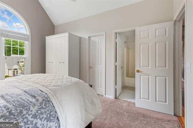 bedroom featuring vaulted ceiling, light carpet, and connected bathroom