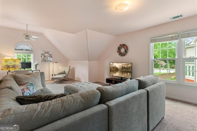 living area featuring baseboards, lofted ceiling, light colored carpet, and a ceiling fan
