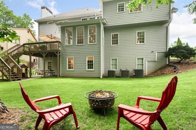 rear view of house featuring a fire pit, a wooden deck, central air condition unit, stairs, and a lawn