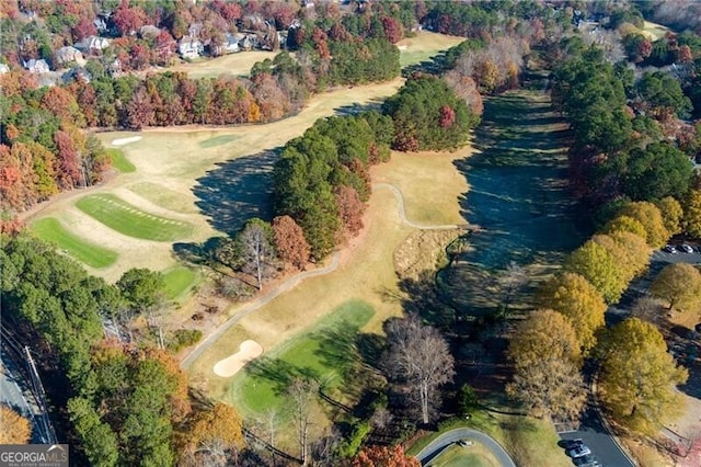aerial view of property and surrounding area featuring a golf club and a tree filled landscape
