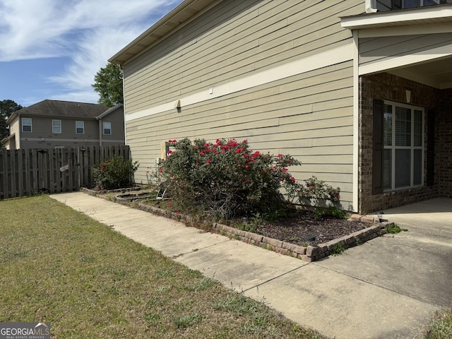 view of side of property featuring brick siding, fence, and a yard