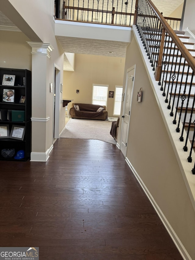 foyer entrance with baseboards, a high ceiling, stairs, and wood finished floors
