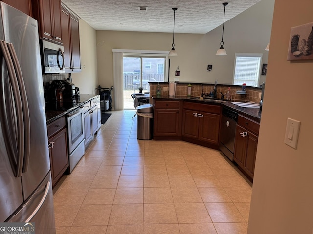 kitchen with a textured ceiling, appliances with stainless steel finishes, a sink, and tasteful backsplash