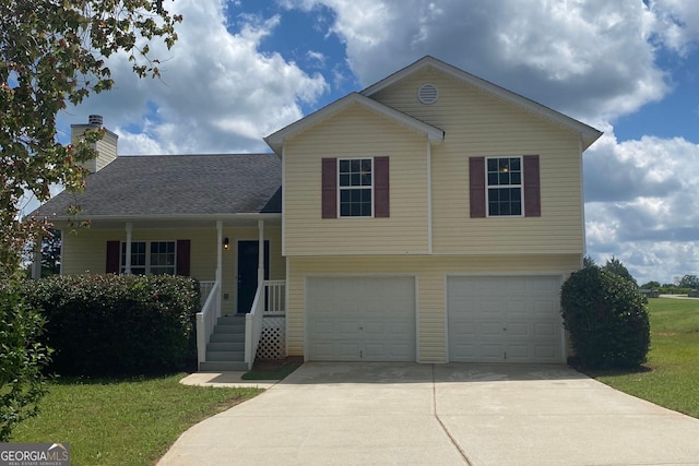split level home featuring concrete driveway, a chimney, a front lawn, and an attached garage