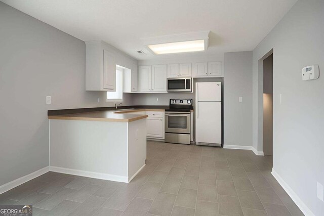 kitchen featuring white cabinetry, baseboards, appliances with stainless steel finishes, and a sink