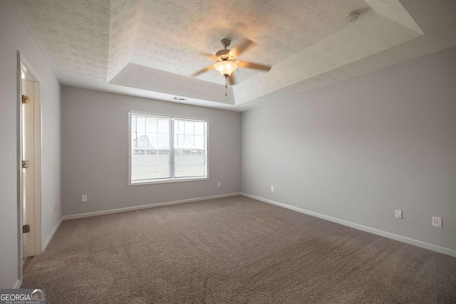 carpeted empty room with baseboards, a textured ceiling, ceiling fan, and a tray ceiling
