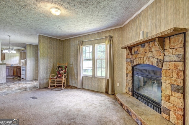 living room with crown molding, carpet flooring, a fireplace, a textured ceiling, and a chandelier